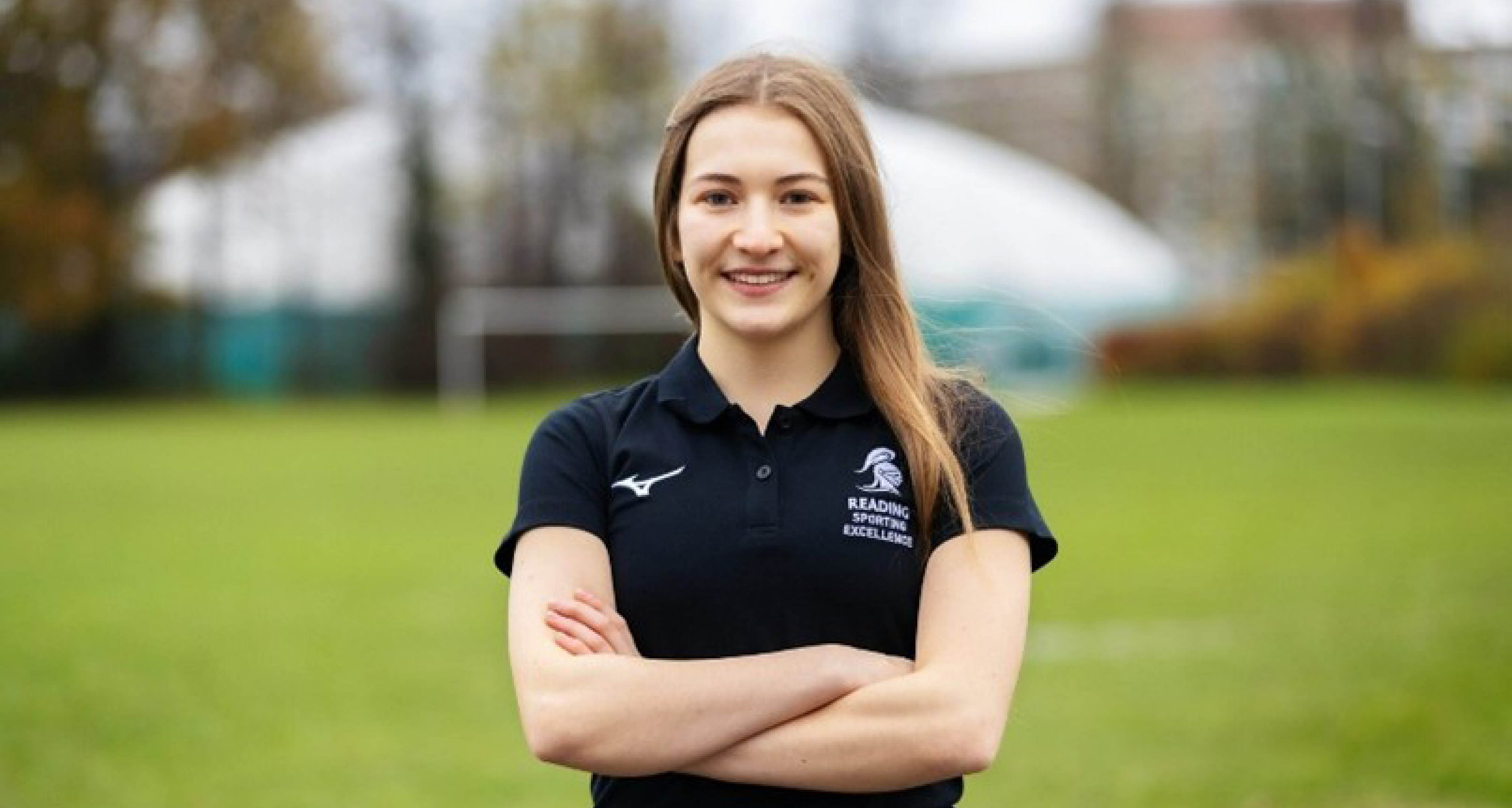 Hannah Niven, smiling to camera, stood in a sports field.