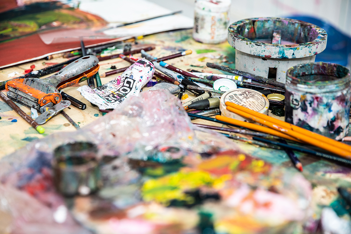 A table strewn with paint and paint brushes