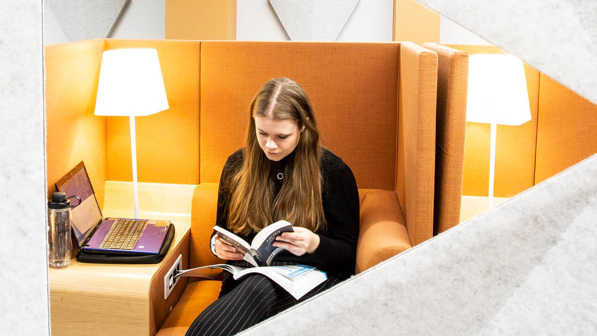 Female student reading a book in a booth in the University library