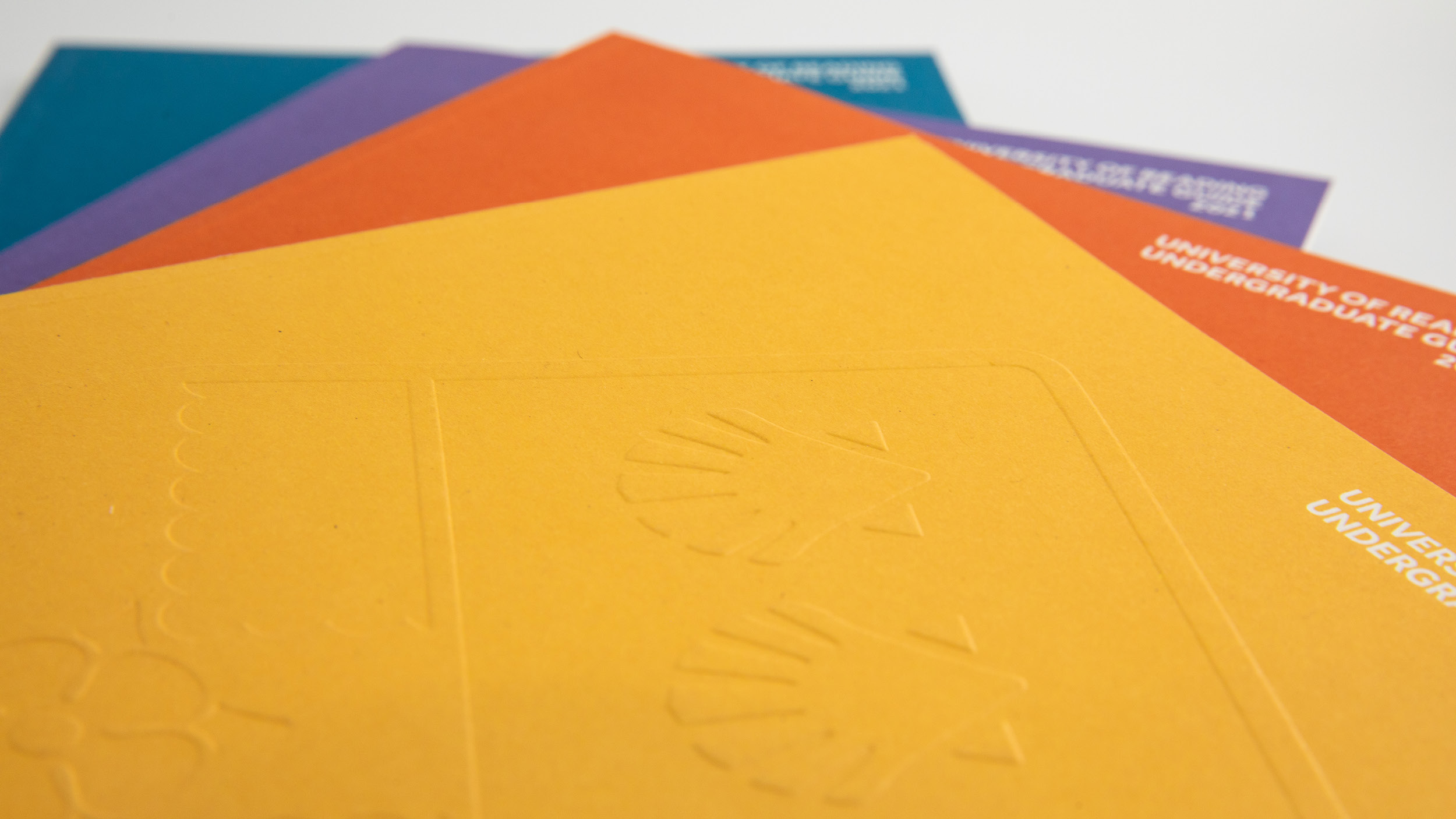 Pile of prospectuses in yellow, orange, purple and teal