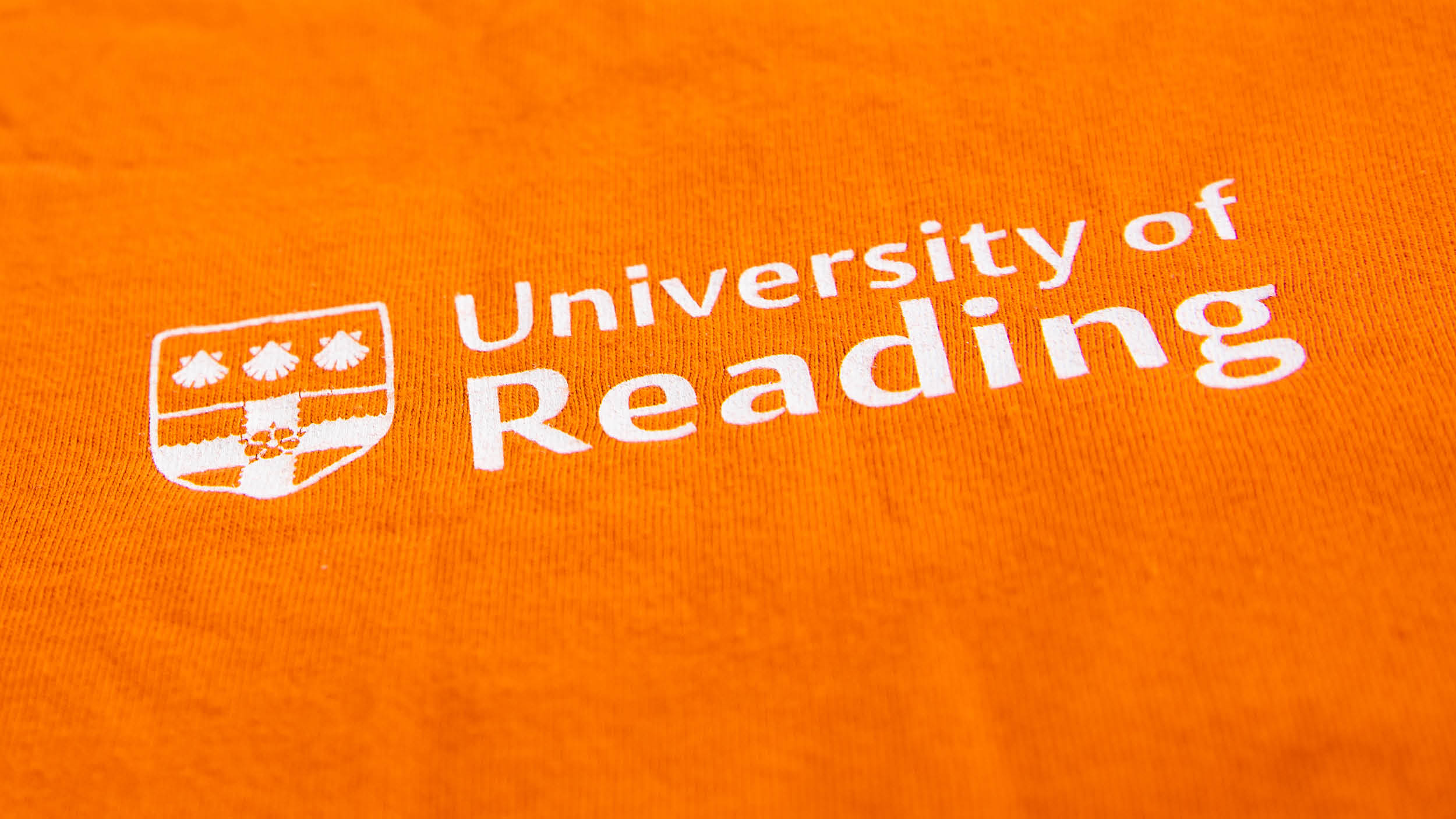 University of Reading logo shown as white screen print on an orange t-shirt