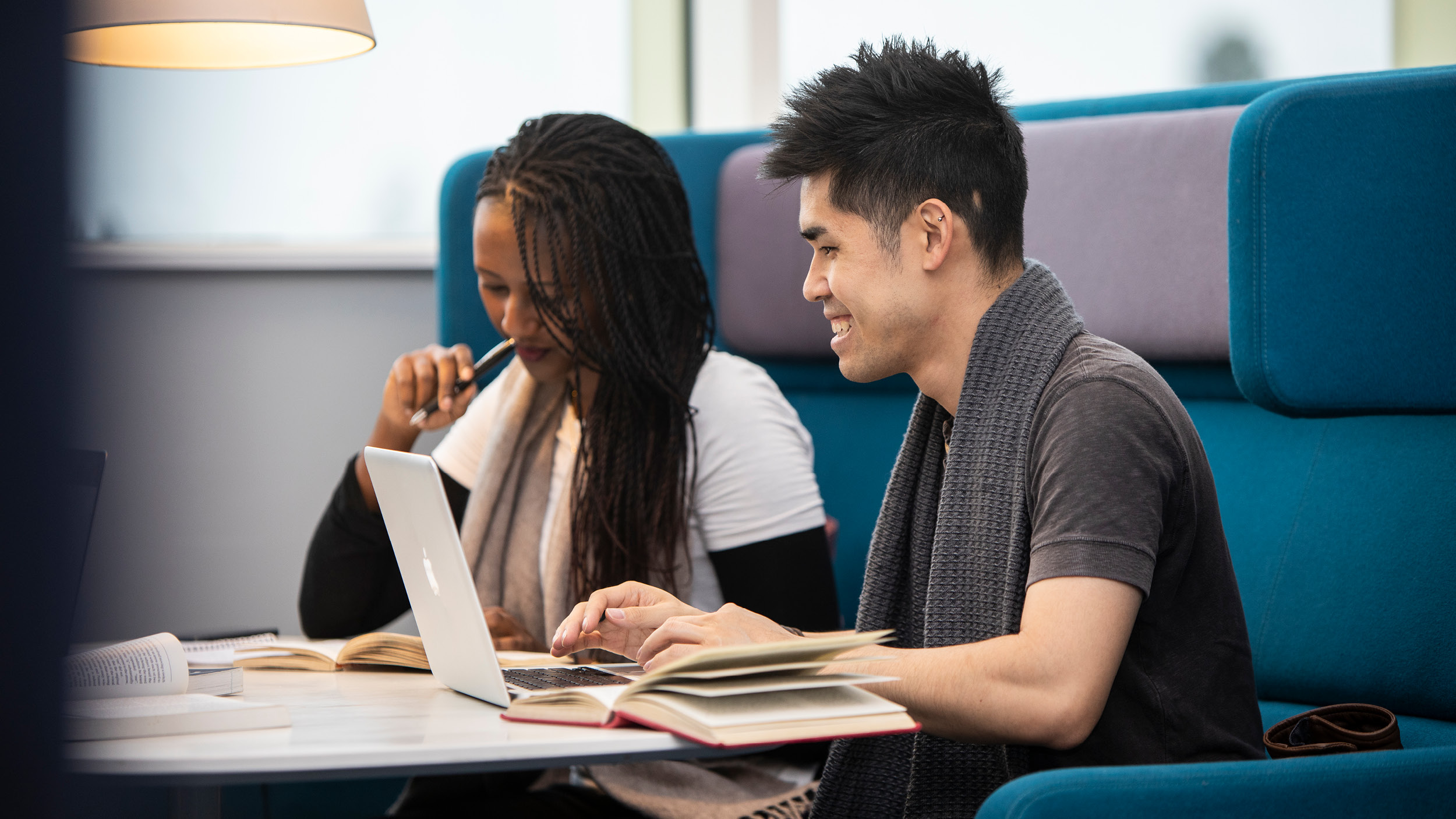 Male and female student study together in a booth in the library