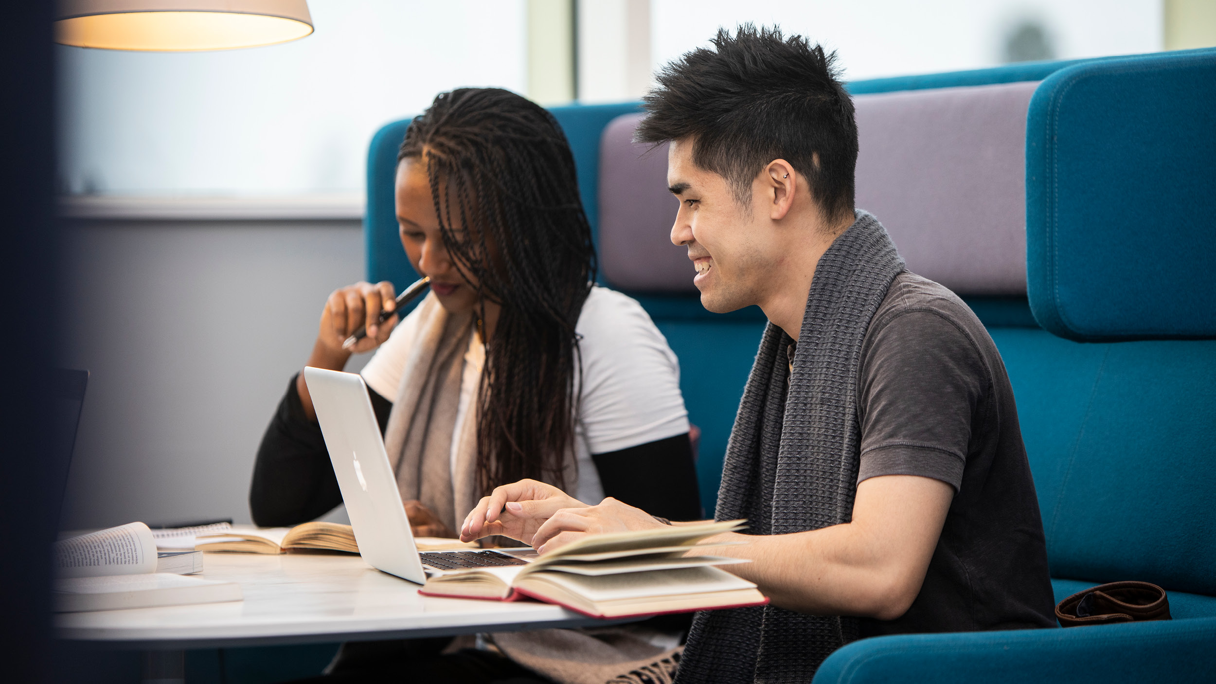Male and female student studying together in a booth in the library