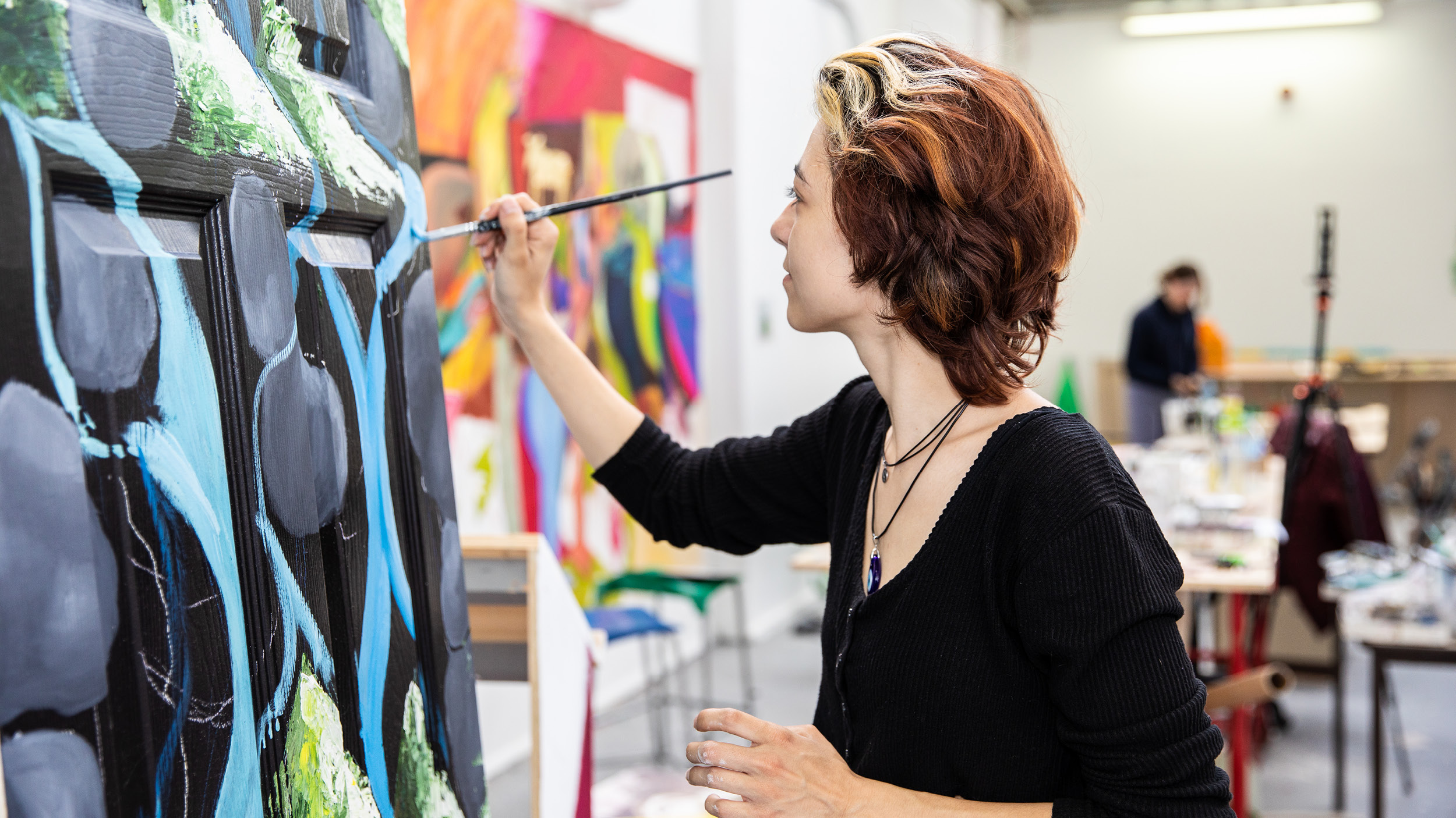 Female student concentrates on painting in the art studio