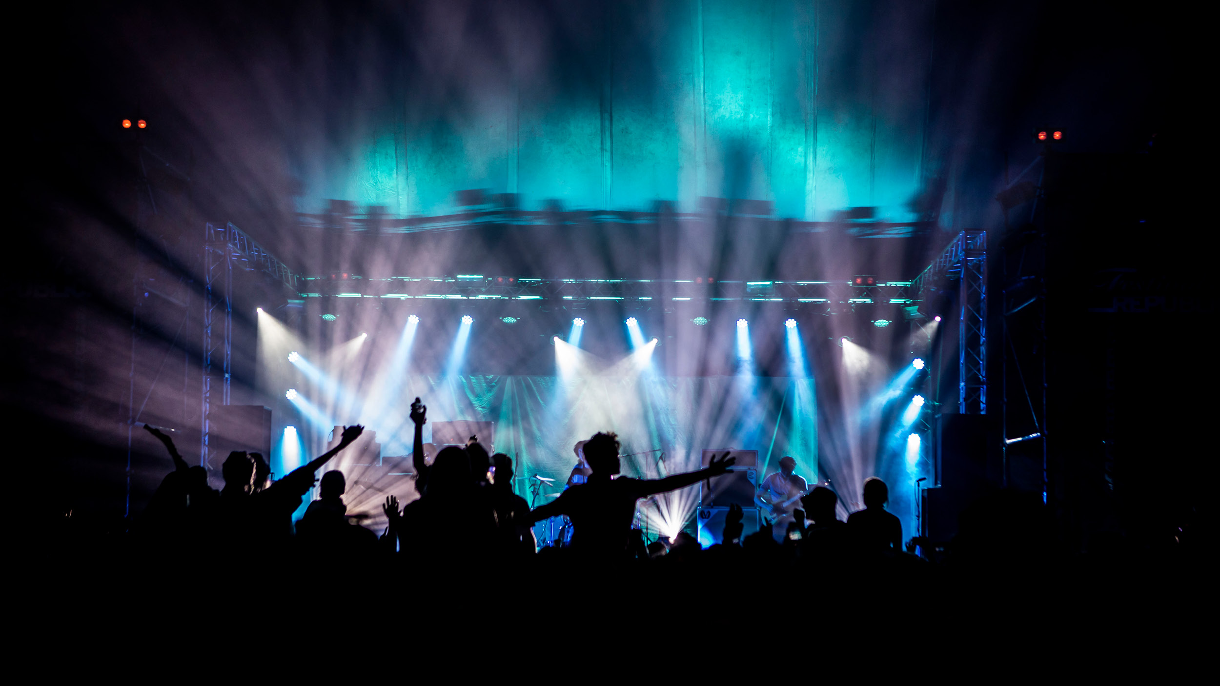 Revellers silhouetted against the bright blue lights of the main stage at Reading Festival