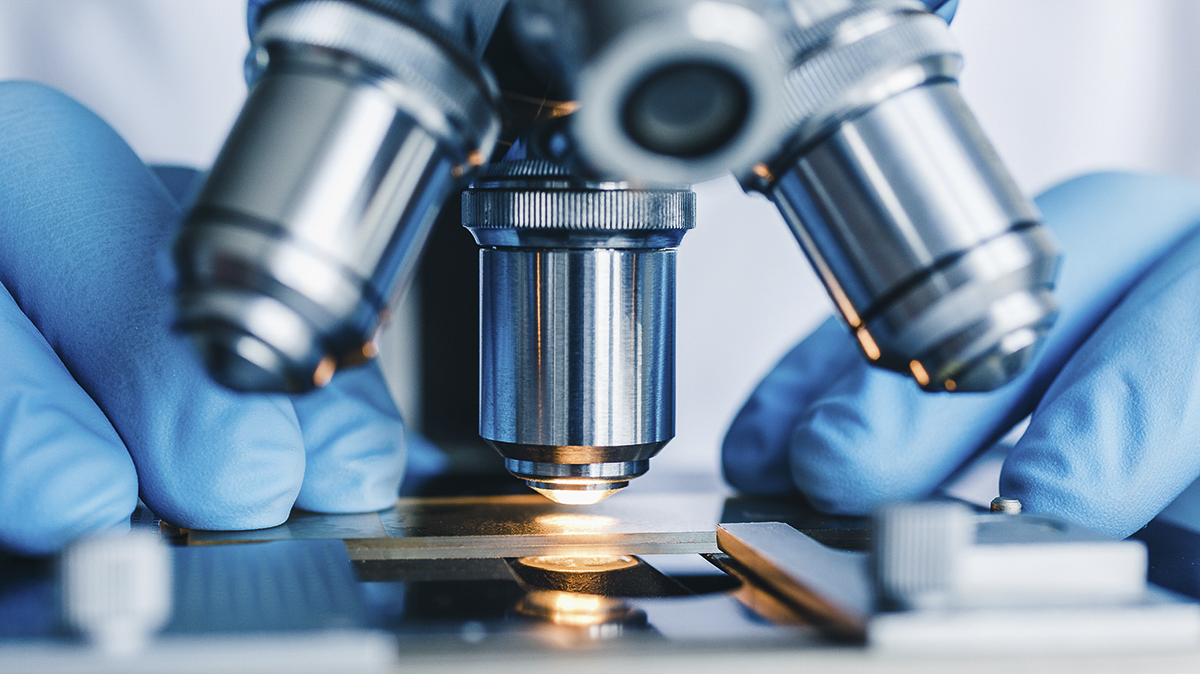 Close-up of scientist's hands on a microscope