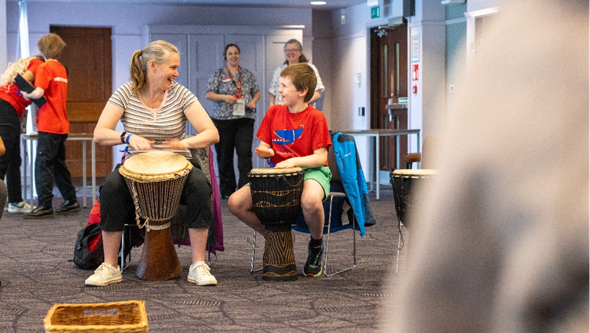 A child and their guardian enjoying an African drumming workshop