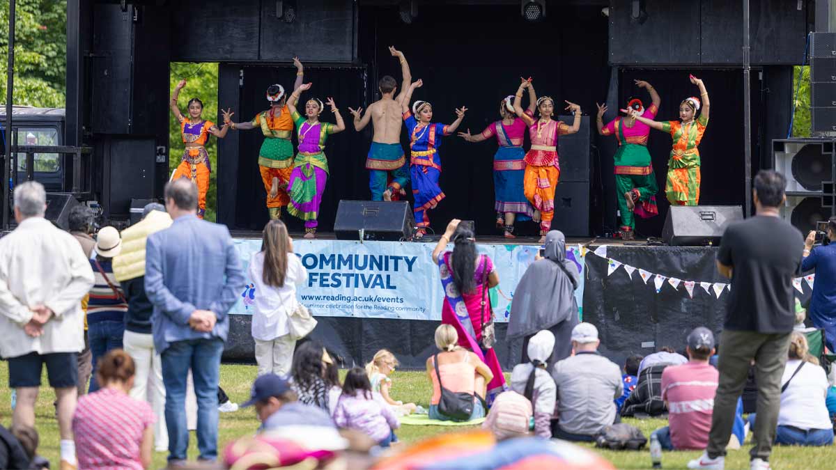 Community Festival 2025, crowd watching the stage where a colourful troupe are dancing.