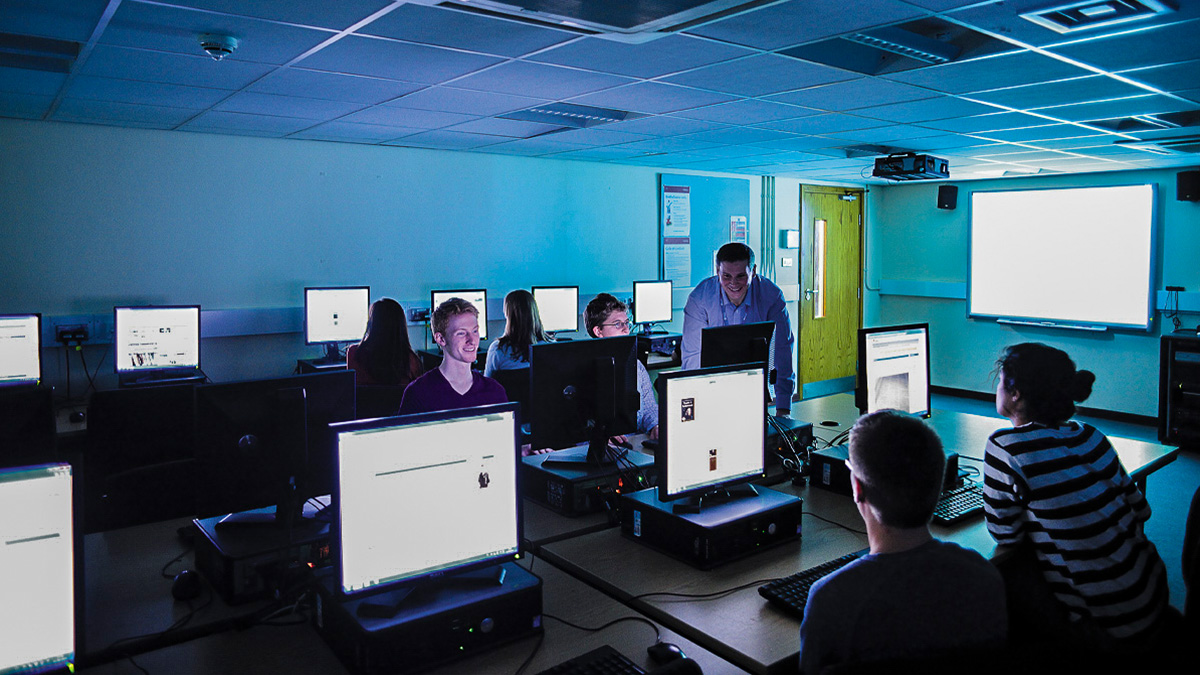 An academic helping students in a practical session in a computer lab