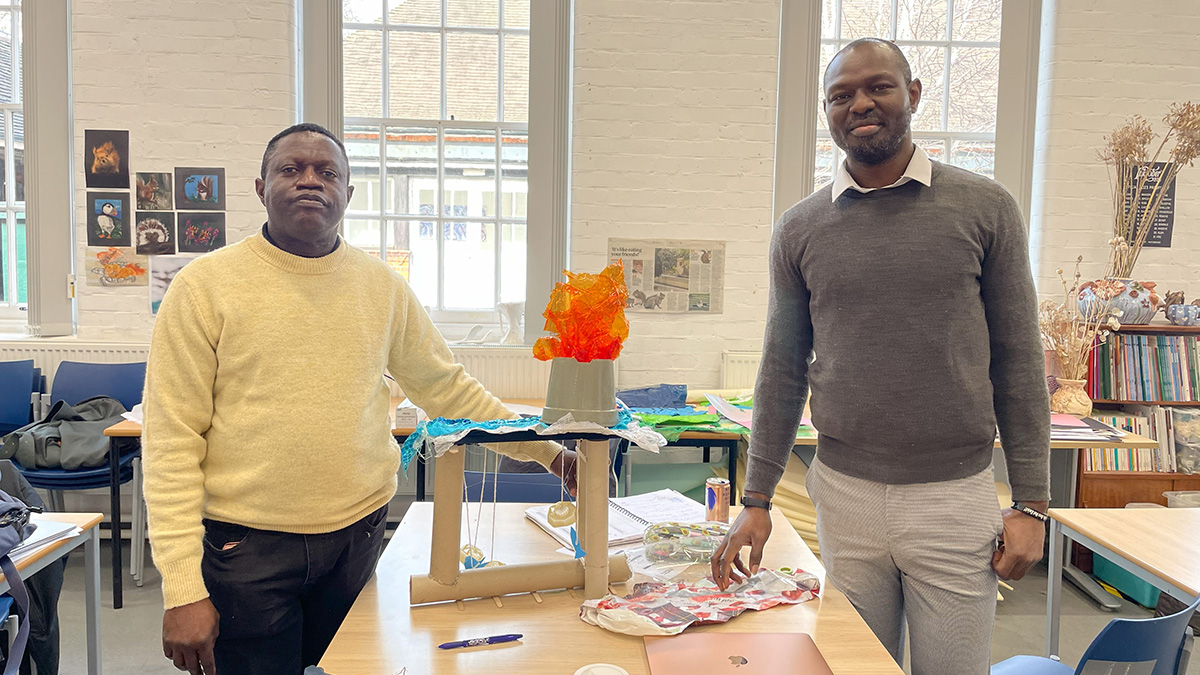 Two of the Institute of Education's international students standing in a classroom next to some schoolwork