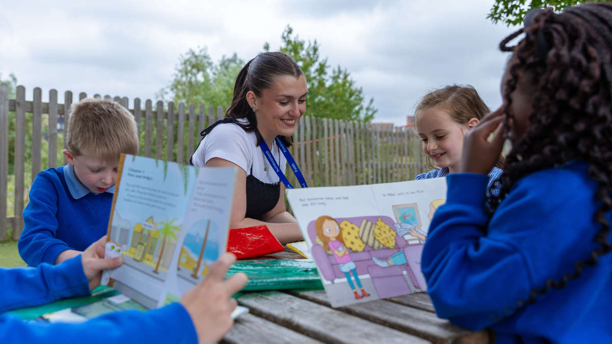 Teacher sat reading with primary school children
