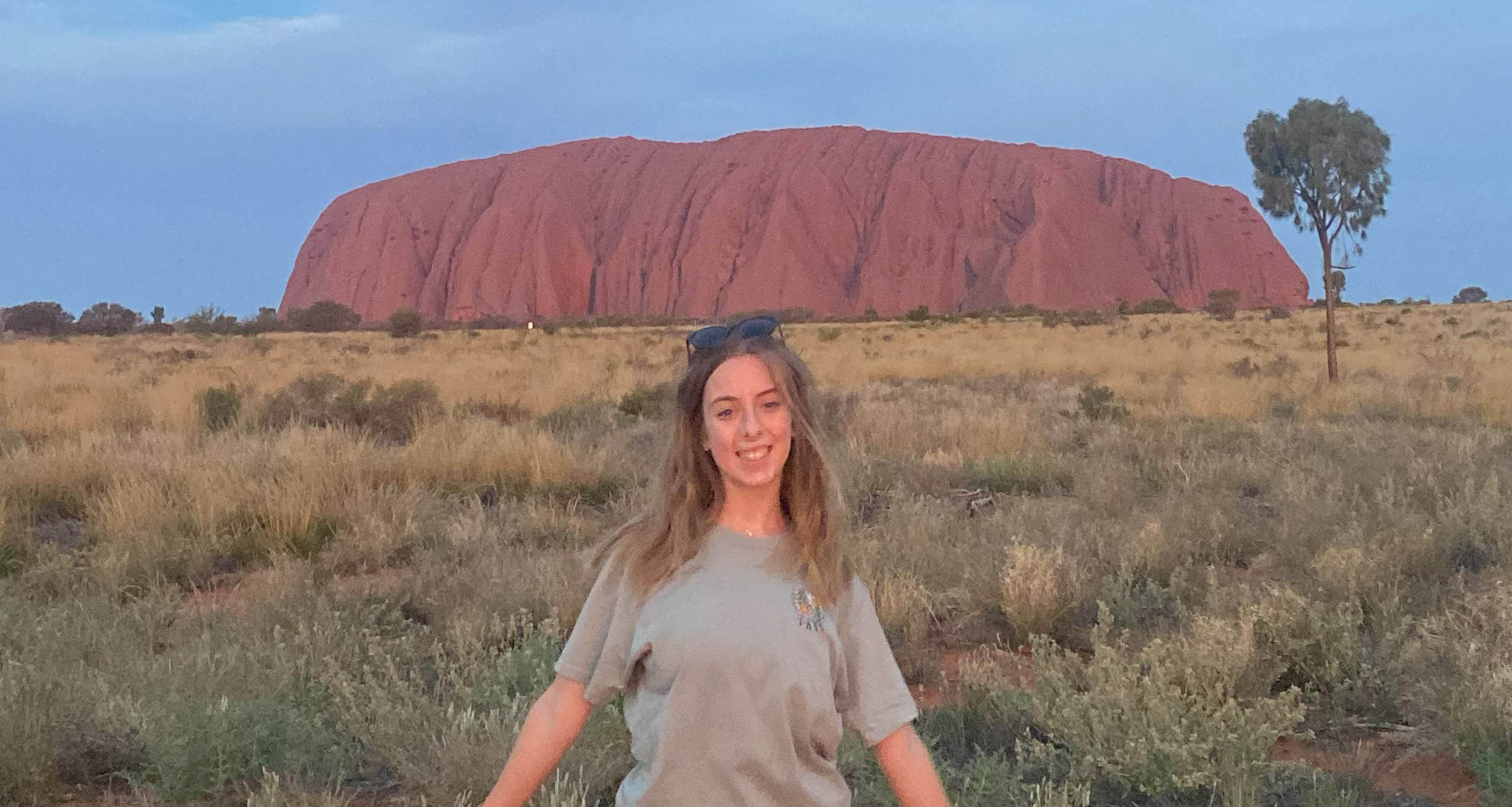 Student Sophie standing in front of Ayers Rock, Australia.