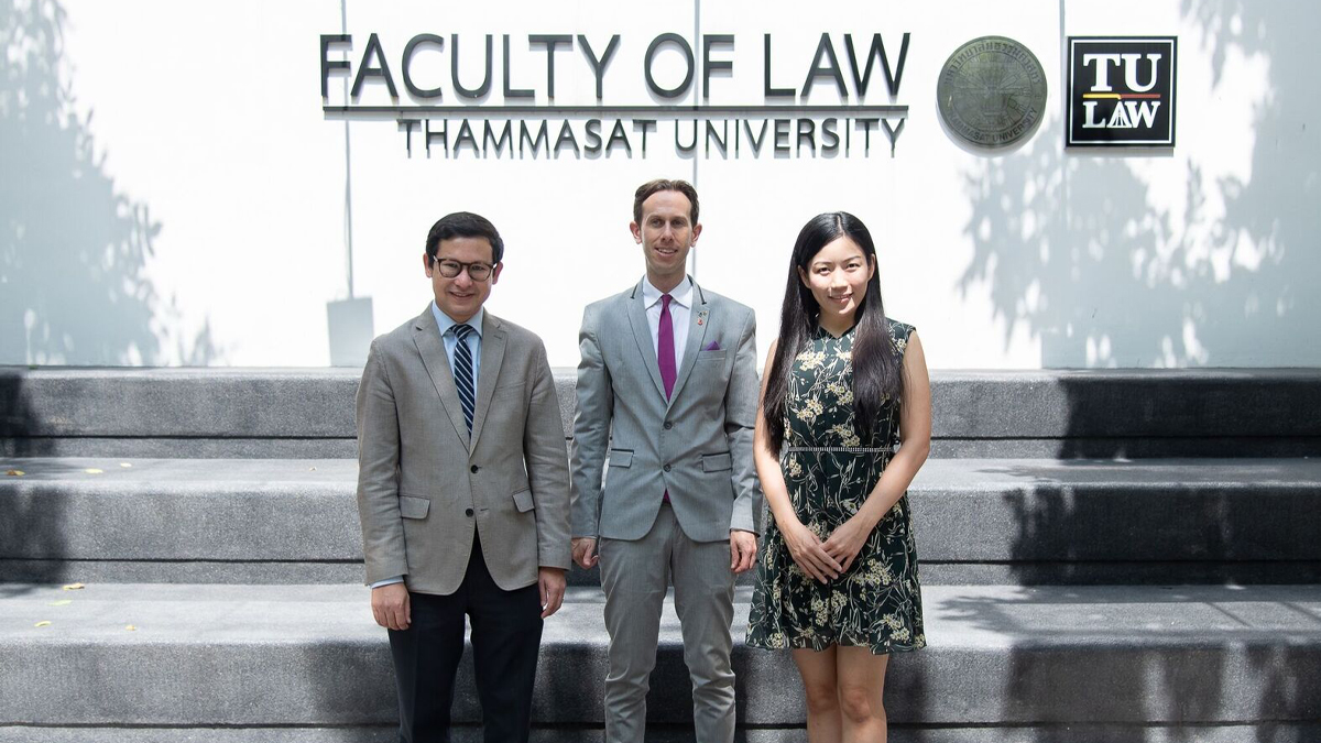 Members of staff standing outside in front of the Faculty of Law, Thammasat University